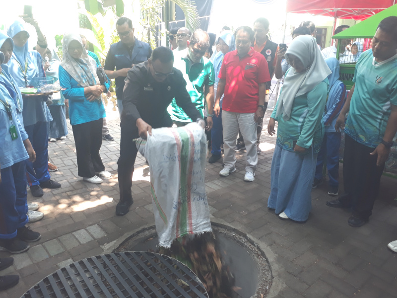 Bambang Suhendro didampingi Winarti, M.Pd memasukkan sampah organik di biopori jumbo SMPN 4 Ponorogo.
